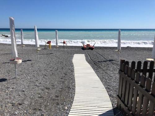 a path on a beach with a fence and the ocean at Hotel Raphael in Bordighera