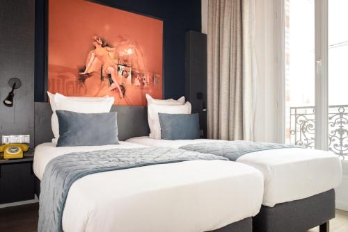 two beds in a bedroom with a painting on the wall at Hôtel Des Arts-Bastille in Paris