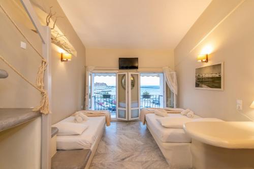 a living room with four white couches and a sink at Fratelli Rooms in Tinos