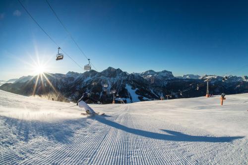 a person skiing down a snow covered slope with a ski lift at Apartment Dui Residence Bun Ste in San Vigilio Di Marebbe