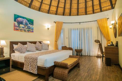 a bedroom with a king sized bed and a table at Hunters Paradise Cottages in Bungoma
