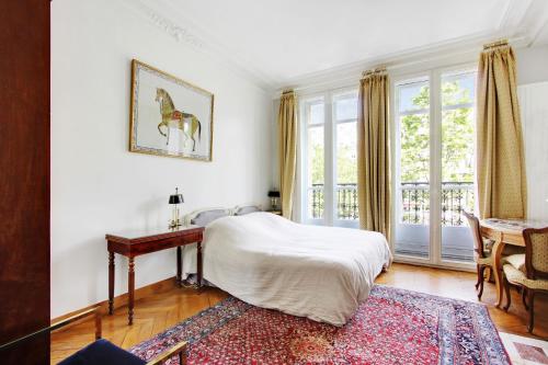 1 dormitorio con cama, escritorio y ventana en Suite junior avec balcon et vue sur Arc de Triomphe en París