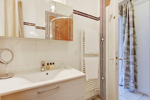 a white bathroom with a sink and a mirror at Suite junior avec balcon et vue sur Arc de Triomphe in Paris