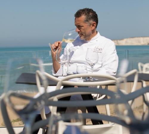 a man sitting at a table with a glass of wine at Luna Minoica Suites and Apartments in Montallegro