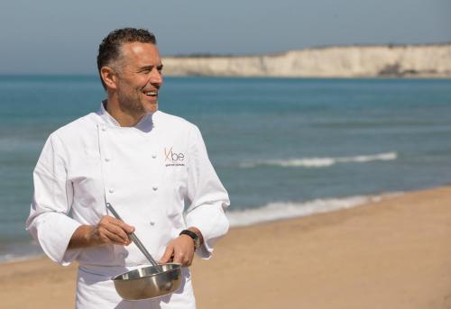 a man holding a bowl on the beach at Luna Minoica Suites and Apartments in Montallegro