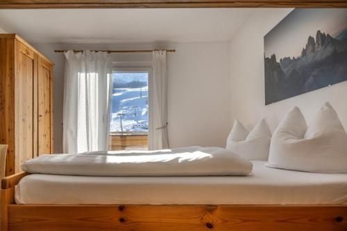 a bedroom with a bed with white pillows and a window at Pension Haunold in San Candido