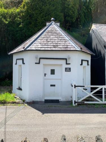 a white garage with a door and a gate at The Welsh Toll House in Carmarthen