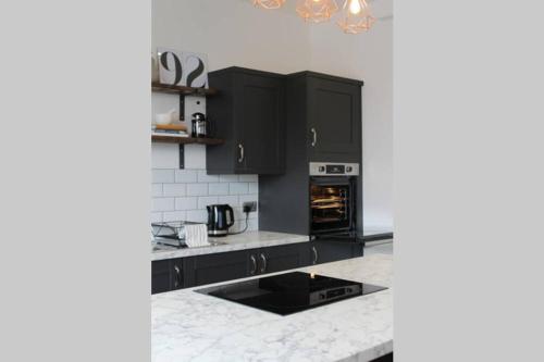 a kitchen with black cabinets and an oven at StayWell Apt By Horizon Stays in Middlesbrough