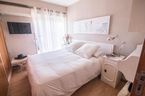 Un dormitorio con una gran cama blanca y una ventana en Beachfront at Perellonet en El Perellonet