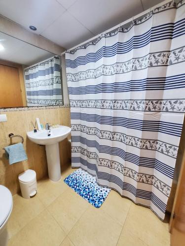 a bathroom with a sink and a shower curtain at Ático dúplex precioso con piscina privada en Paraíso de Vera! in Vera