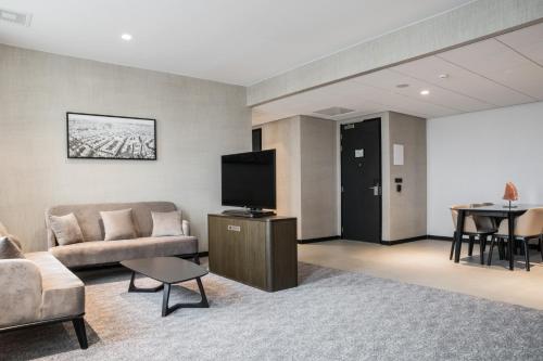 a living room with a couch and a tv at Radisson Hotel & Suites Amsterdam South in Amstelveen