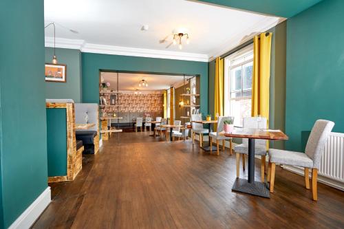 uma sala de jantar com paredes verdes e mesas e cadeiras em The Buxted Inn em Buxted
