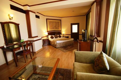 a hotel room with a bed and a couch and a table at Hotel President in Jalandhar