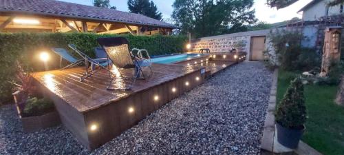 a backyard with a deck with lights and a swimming pool at La Maison des Vignes in Charentay