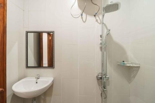a white bathroom with a sink and a shower at RedDoorz @ Hotel Copacobana Bengkulu in Bengkulu