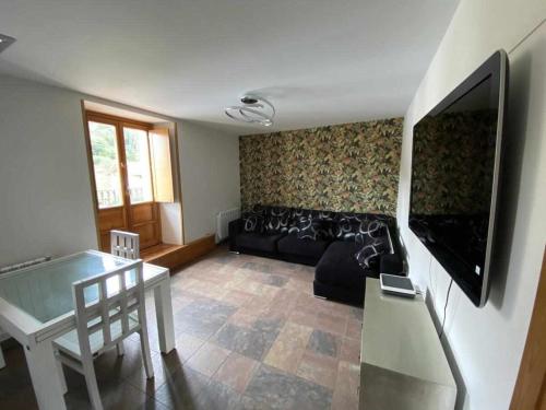 ein Wohnzimmer mit einem schwarzen Sofa und einem TV in der Unterkunft Camino del Norte vivienda turística ubicada en Pobeña in Poveña