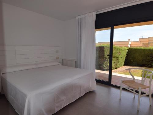 a bedroom with a bed and a chair and a window at Villa els ametllers in Sant Feliu de Guíxols