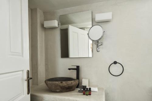 a bathroom with a stone sink and a mirror at Mr and Mrs White Oia - Santorini in Oia