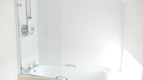 a white bathroom with a tub and a mirror at Arndean Cottages in Dollar