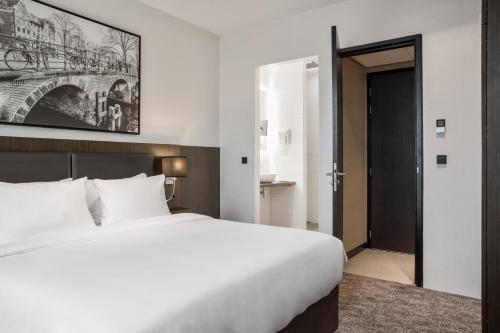 a bedroom with a large white bed and a doorway at Radisson Hotel & Suites Amsterdam South in Amstelveen
