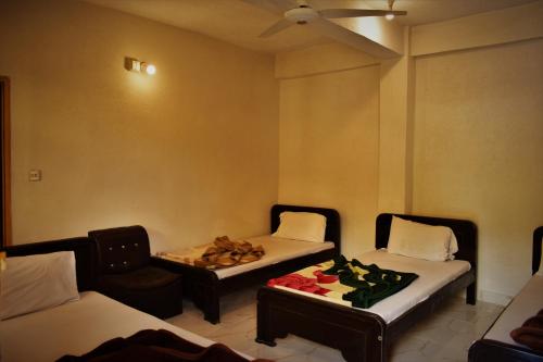 a room with two beds and a couch and a table at Bypass Hotel in Swat