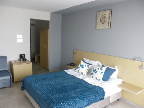 a bedroom with a bed with a blue blanket and pillows at Albizia Beach Hotel in Varna City