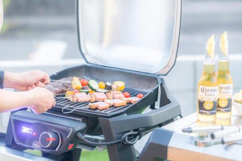 a person grilling meat and vegetables on a grill at West Coast Villa Shirahama in Shirahama