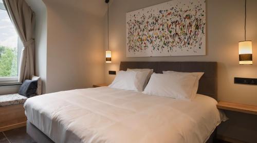 JodoigneにあるLa Villa du Hautsartの白いベッドと壁に絵画が飾られたベッドルーム1室
