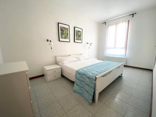 a white bedroom with a bed and a window at Beachside Family Garden Retreat in Cavallino-Treporti