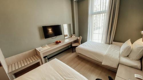 a small room with a bed and a television at Resident City Hotel in Almaty