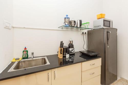 a kitchen with a sink and a refrigerator at BluO Studio Koramangala - Terrace Garden, Parking in Bengaluru