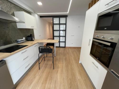 a kitchen with white cabinets and a wooden table at Oktheway Pedro Saco Street in Sarria