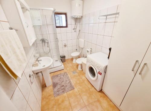 a bathroom with a toilet sink and a washing machine at Bay Terrace Apartment in Donji Stoliv
