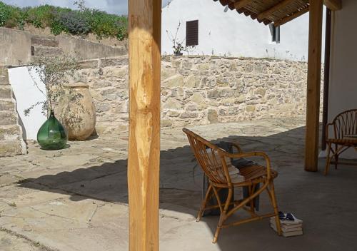 a chair sitting on a patio with a stone wall at Albergo Rurale Casa Fois in Valledoria