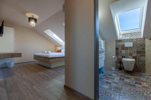 a bedroom with a bed and a bathroom with a window at Penzion a restaurace Feldsberg in Valtice