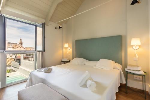 um quarto com uma cama branca e uma grande janela em Kayser Premium Suites em Sevilha
