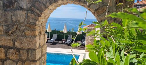 a view of the pool and the ocean from a stone wall at Hotel Palata Venezia in Ulcinj