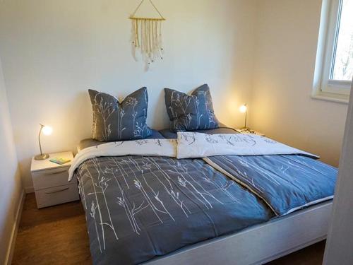 a bedroom with a bed with blue sheets and a window at Ferienhaus Sonnenufer in Rheinsberg