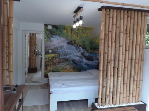 Bett in einem Zimmer mit einem Gemälde eines Wasserfalls in der Unterkunft Casa Bambus Sovata 1 in Sovata