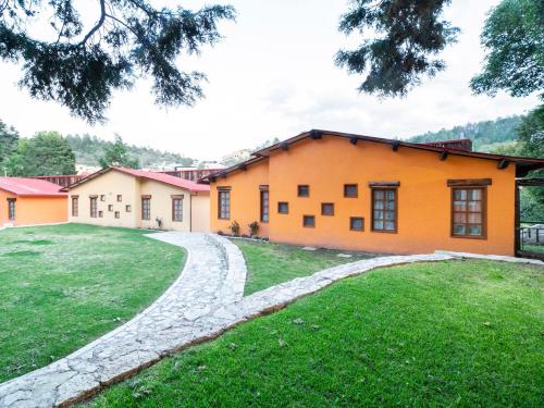 an orange house with a stone driveway at Hotel Casona de Minas in Mineral del Monte