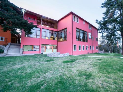 a pink building with a large yard in front of it at Hotel Casona de Minas in Mineral del Monte