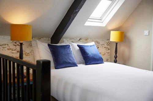 a bedroom with a bed with blue pillows and two lamps at Old Manse Hotel by Greene King Inns in Bourton on the Water