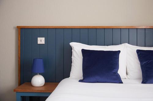 a bed with blue and white pillows and a blue wall at Old Manse Hotel by Greene King Inns in Bourton on the Water
