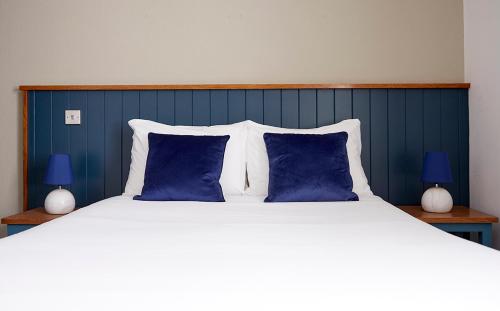 a bedroom with a large bed with blue and white pillows at Old Manse Hotel by Greene King Inns in Bourton on the Water