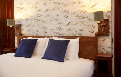a bedroom with a bed with two blue pillows at Old Manse Hotel by Greene King Inns in Bourton on the Water