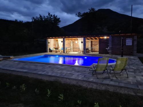 a swimming pool at night with two chairs around it at Holiday Home Faruk in Račić