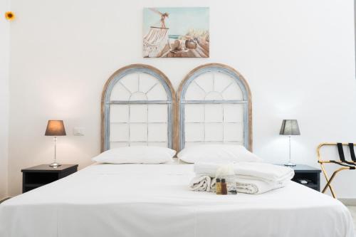 sypialnia z dużym białym łóżkiem i 2 oknami w obiekcie Poggiamico Guest House w mieście Favignana