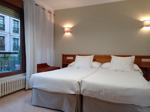 カンガス・デ・オニスにあるHospedaje Torreónのベッドルーム1室(白いシーツが備わるベッド2台、窓付)