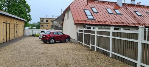 a red car parked in a driveway next to a house at Home away home in Tartu