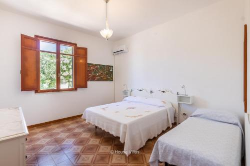 a white bedroom with two beds and a window at House&Villas - Due Palme in Siracusa